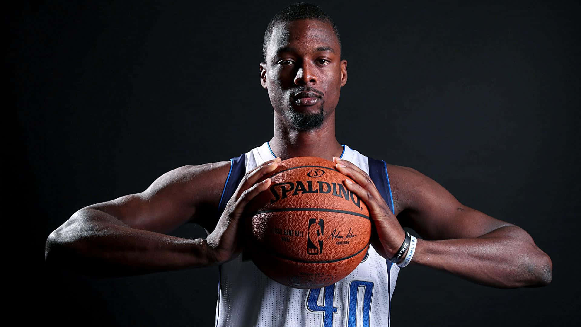 哈里森·巴恩斯 NBA 达拉斯獨行俠 壁紙 — 一名身穿白色球衣的籃球運動員在深色攝影棚背景下手持Spalding籃球。