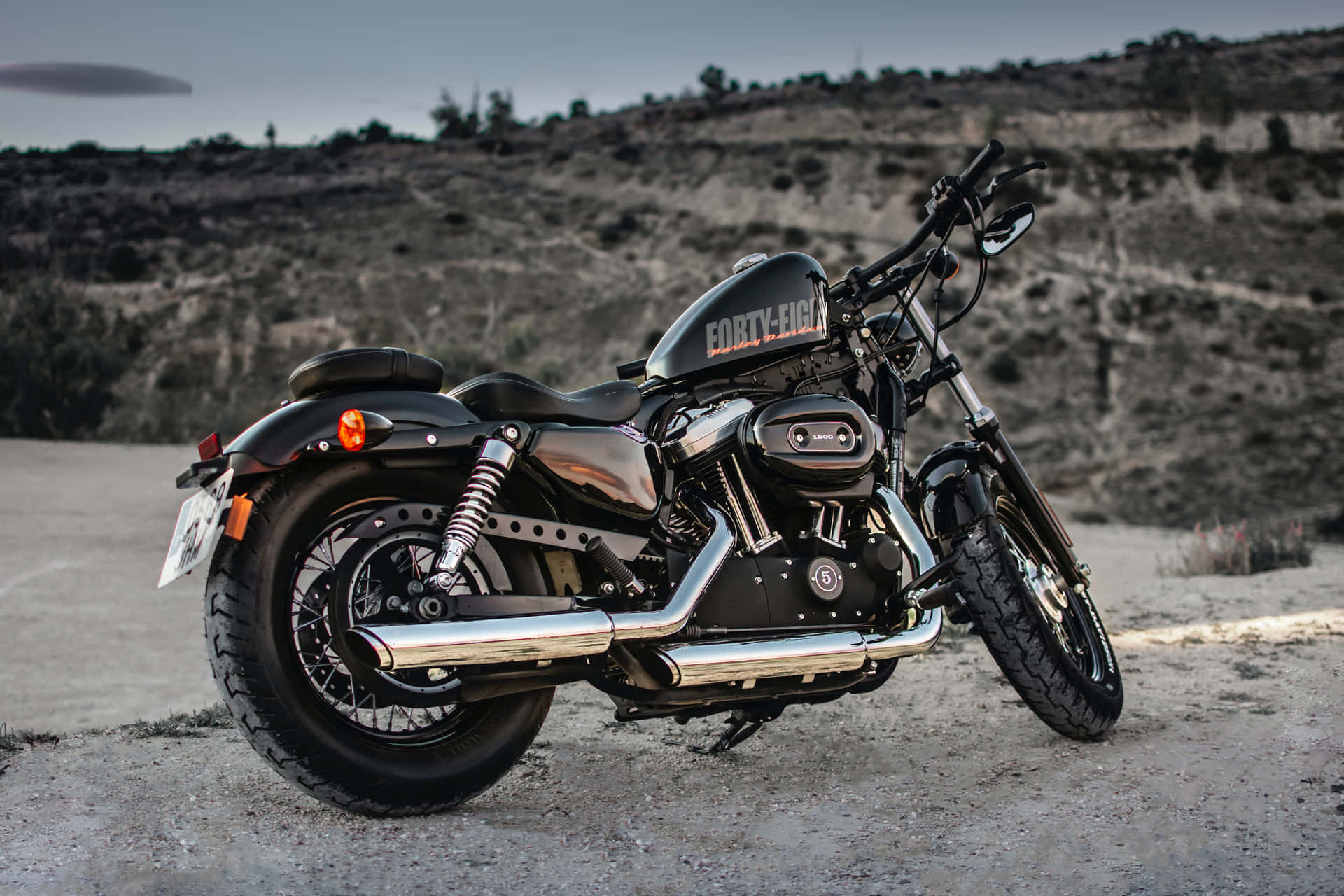 黑色Harley-Davidson Forty-Eight電單車在黃昏時停泊在泥路上。
