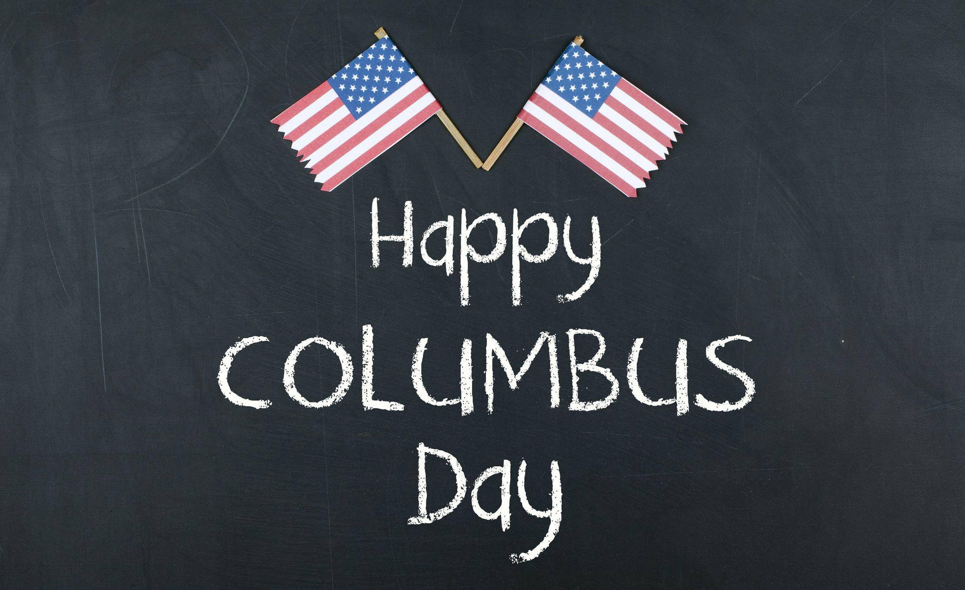黑板上有交叉的美國國旗和粉筆寫的「Happy Columbus Day」。