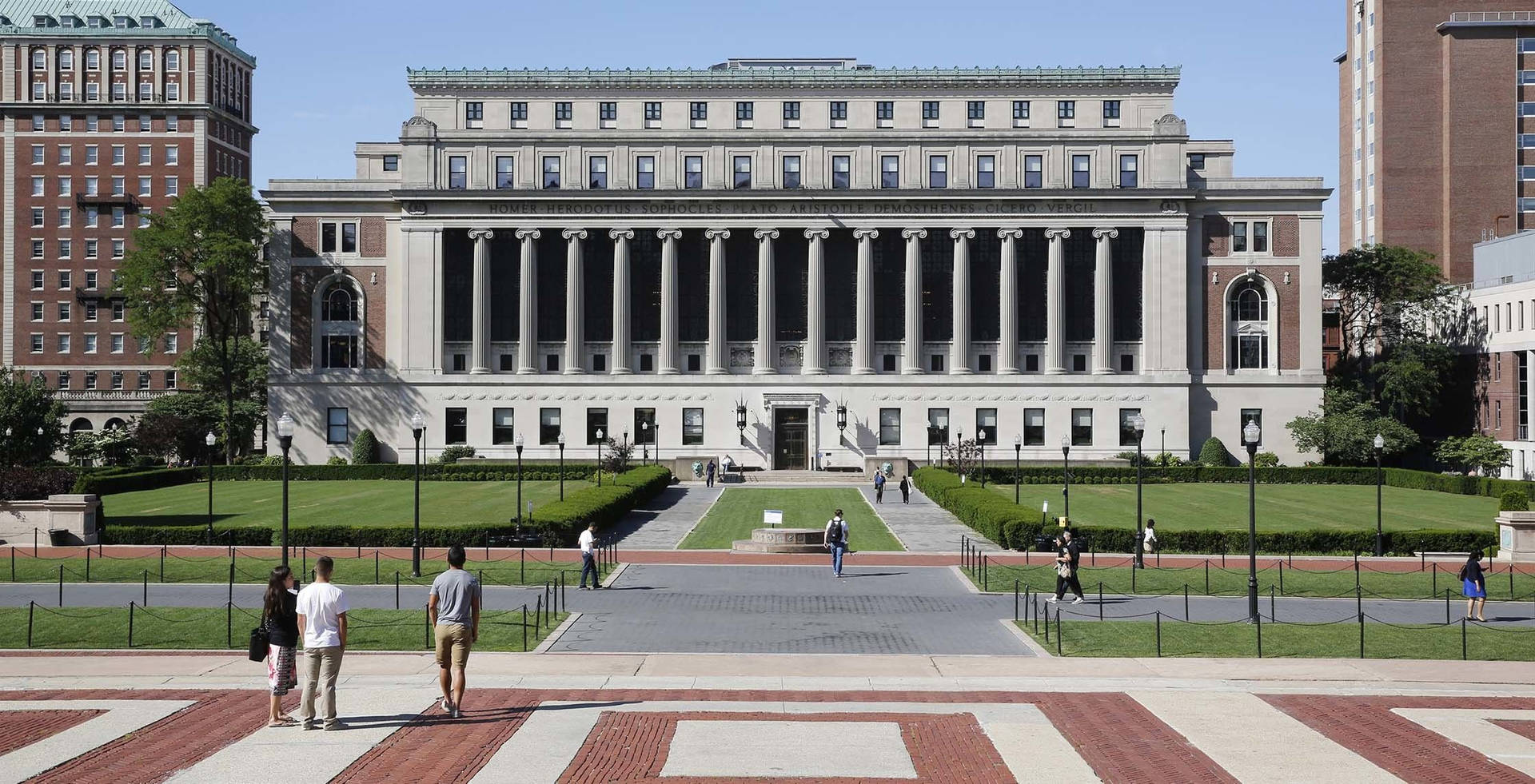 學生們在磚砌廣場上走向帶有柱子的宏偉大學建築。