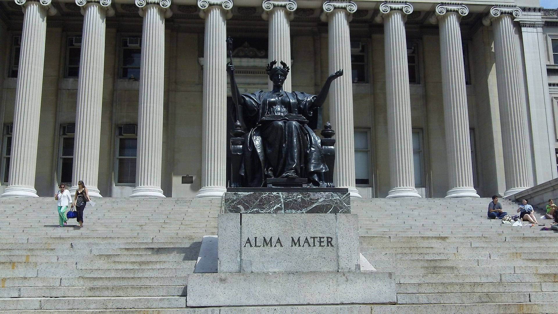 黑色Alma Mater雕像在石階上，前方是古典建築，附近有人。