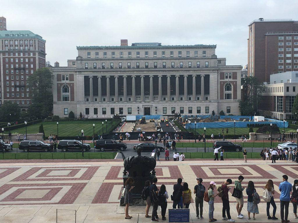 學生們聚集在帶有柱廊的大型大學建築前的圖案廣場上。