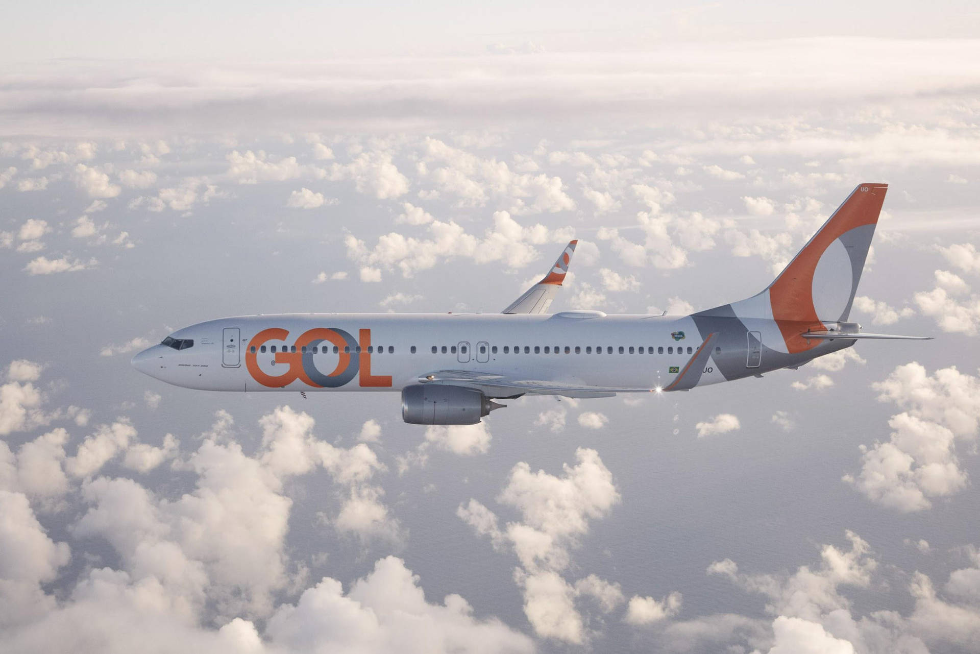 哥倫比亞航空飛越雲層 壁紙 — GOL航空的客機在柔和的天空下，優雅地翱翔於大片蓬鬆的白雲之上。
