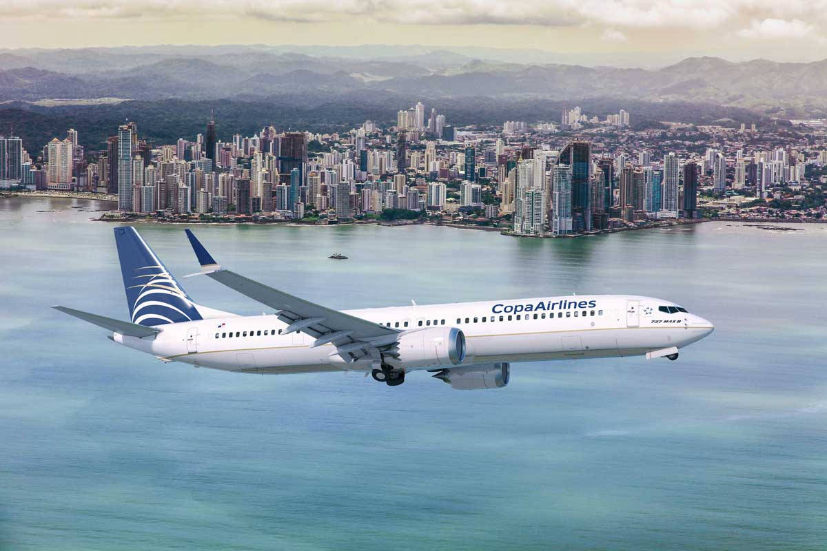 巴拿馬航空飛機飛越沿海城市，遠處有山巒。