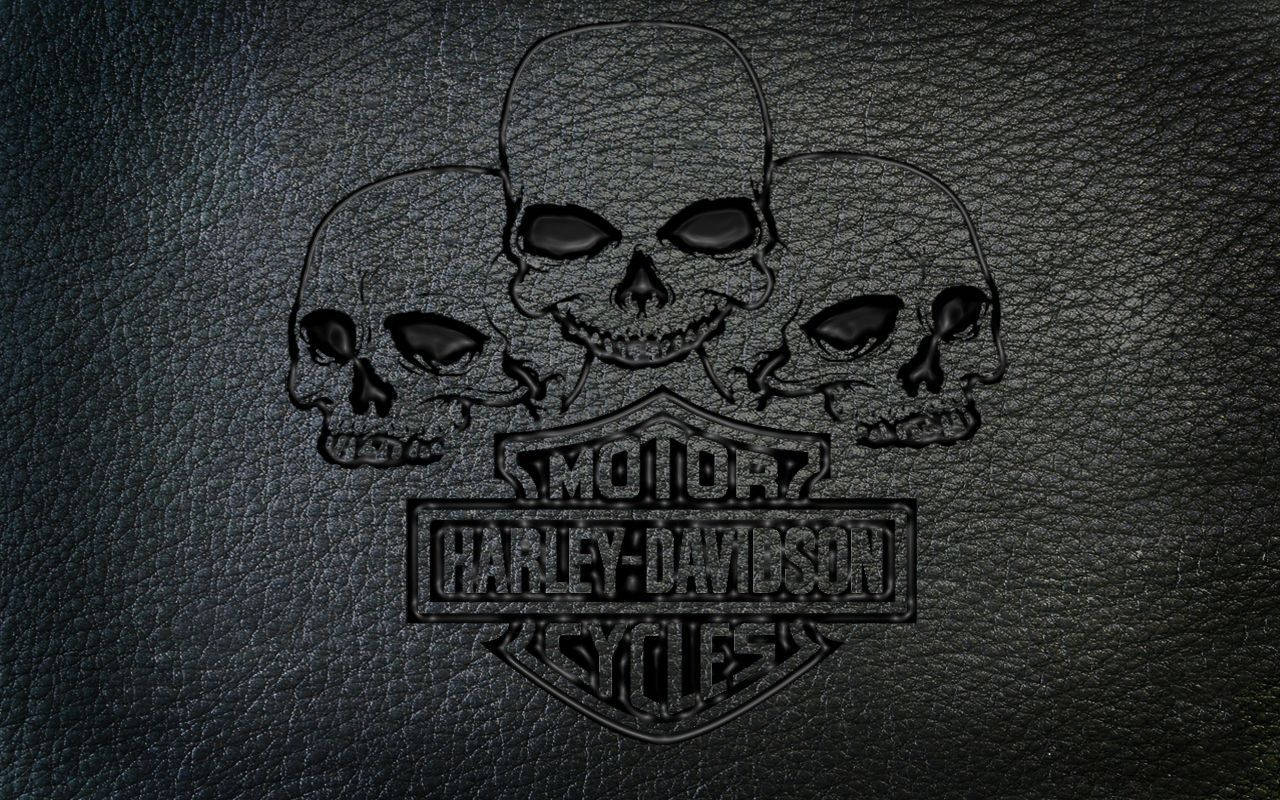 哥德風哈雷戴維森標誌 壁紙 — Harley-Davidson 標誌，三個骷髏頭壓印在深色紋理皮革背景上。