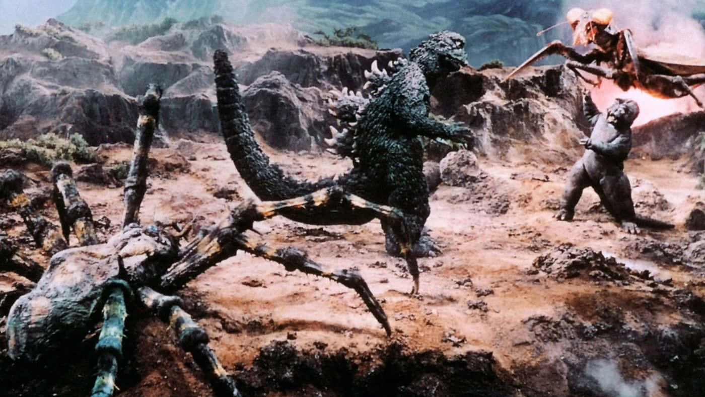 Classic Godzilla 桌布 壁紙 — 哥斯拉在崎嶇的山地地形中與巨型蜘蛛和蛾狀怪獸戰鬥，煙霧和碎片四散。