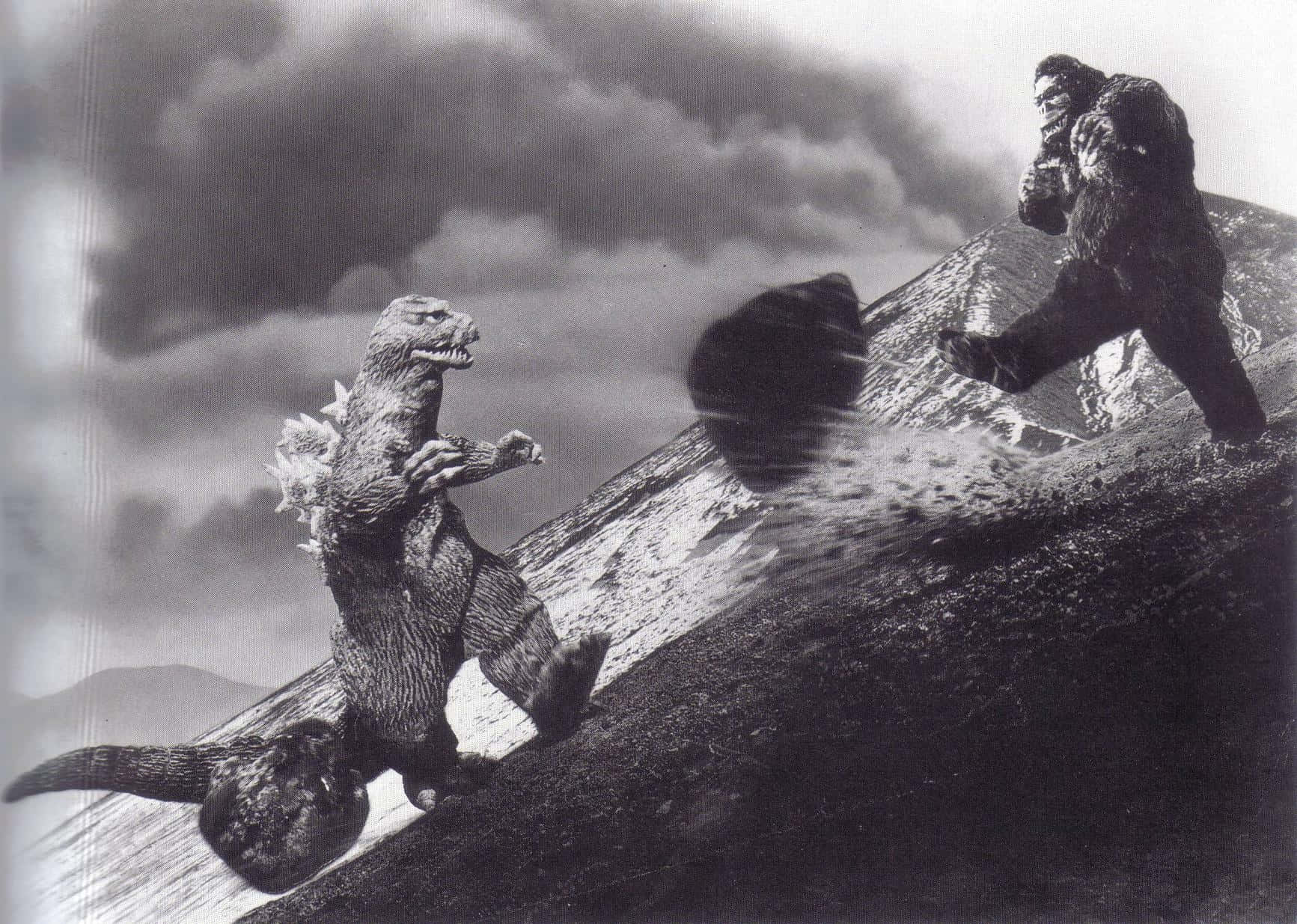 Godzilla Vs Kong 桌布 壁紙 — 哥斯拉與金剛在風暴天空下的雪山頂上衝突，經典黑白怪獸電影場景。