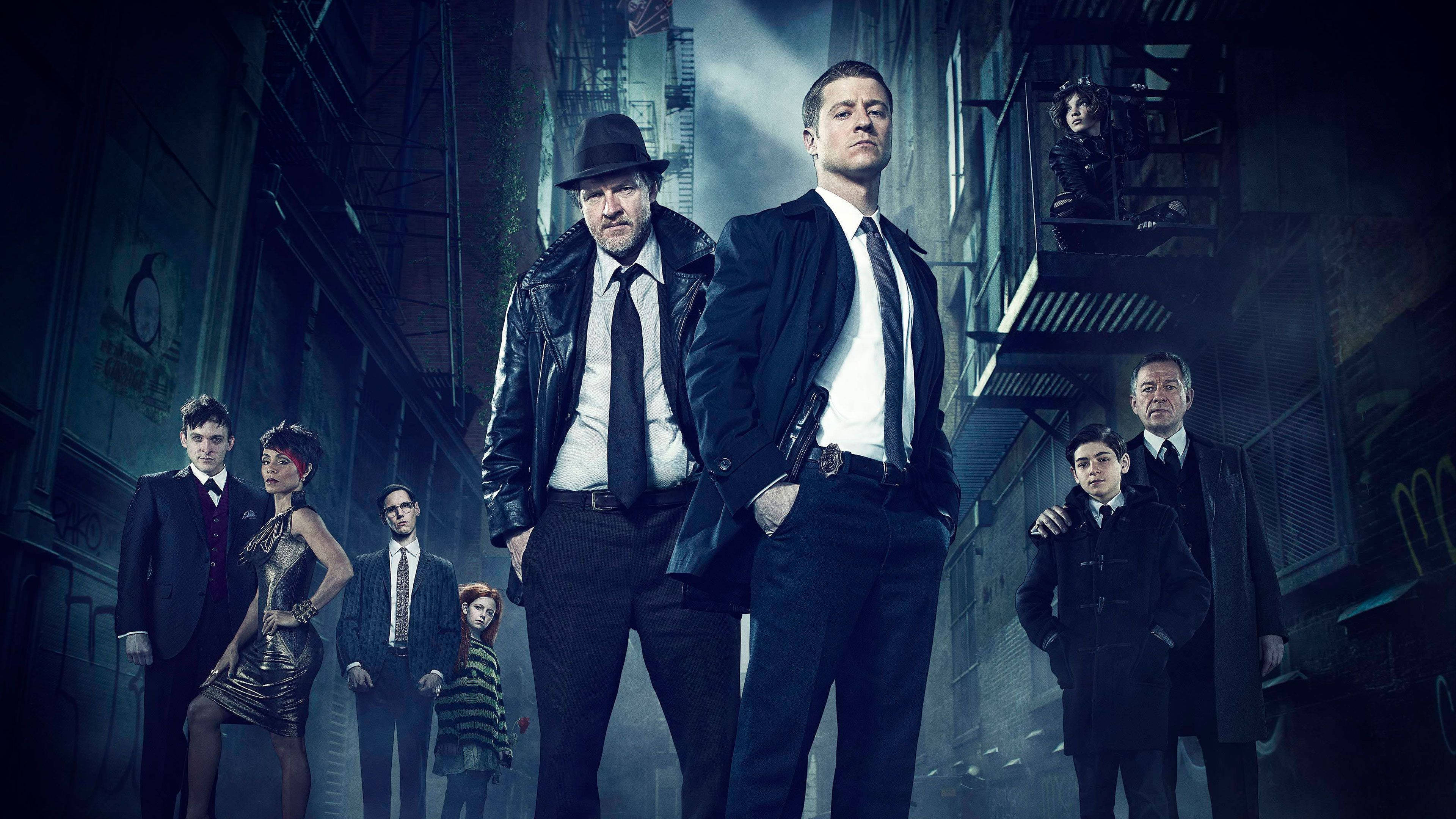 《哥譚》Jim Gordon 暗巷群像 壁紙 — 一個骯髒的城市小巷場景，一群穿著深色西裝和風衣的角色在戲劇性的藍色燈光下擺姿勢。