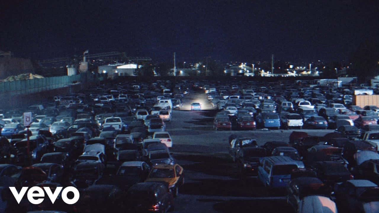 擁擠停車場的夜景，停放的車輛和遠處的工業燈光。