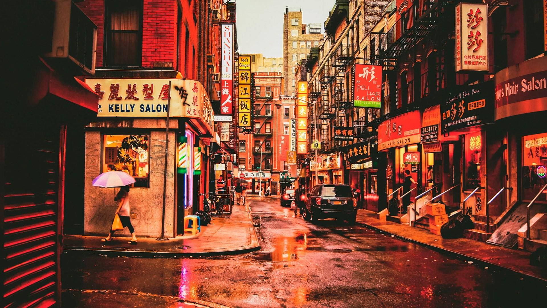 唐人街人行道攝影 壁紙 — 一條雨中的城市小巷，被中文招牌的溫暖霓虹燈光沐浴，倒映在濕漉漉的路面上。