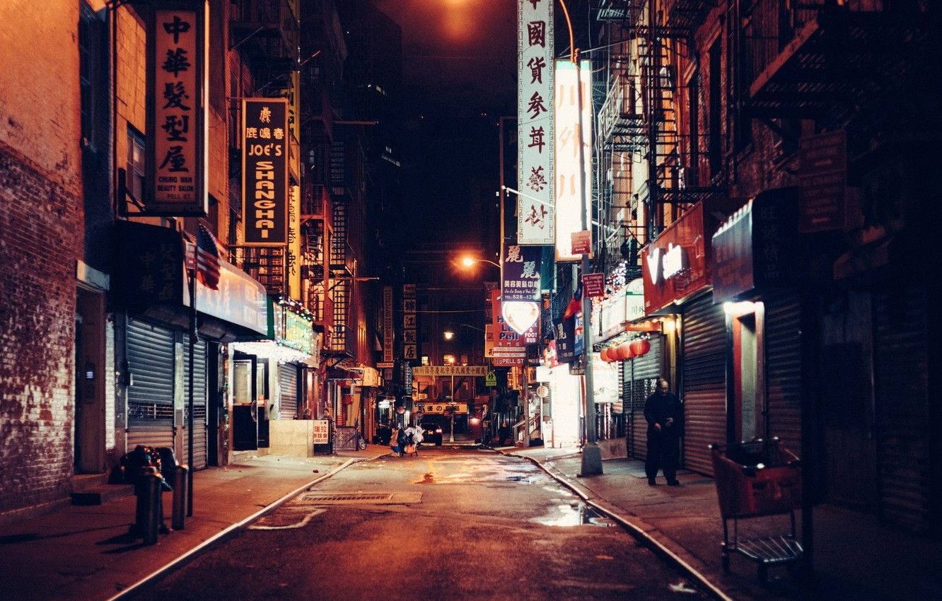 唐人街電影感街景 壁紙 — 夜晚一條狹窄的霓虹燈小巷，有發光的招牌和潮濕的路面反射著溫暖的橙色燈光。