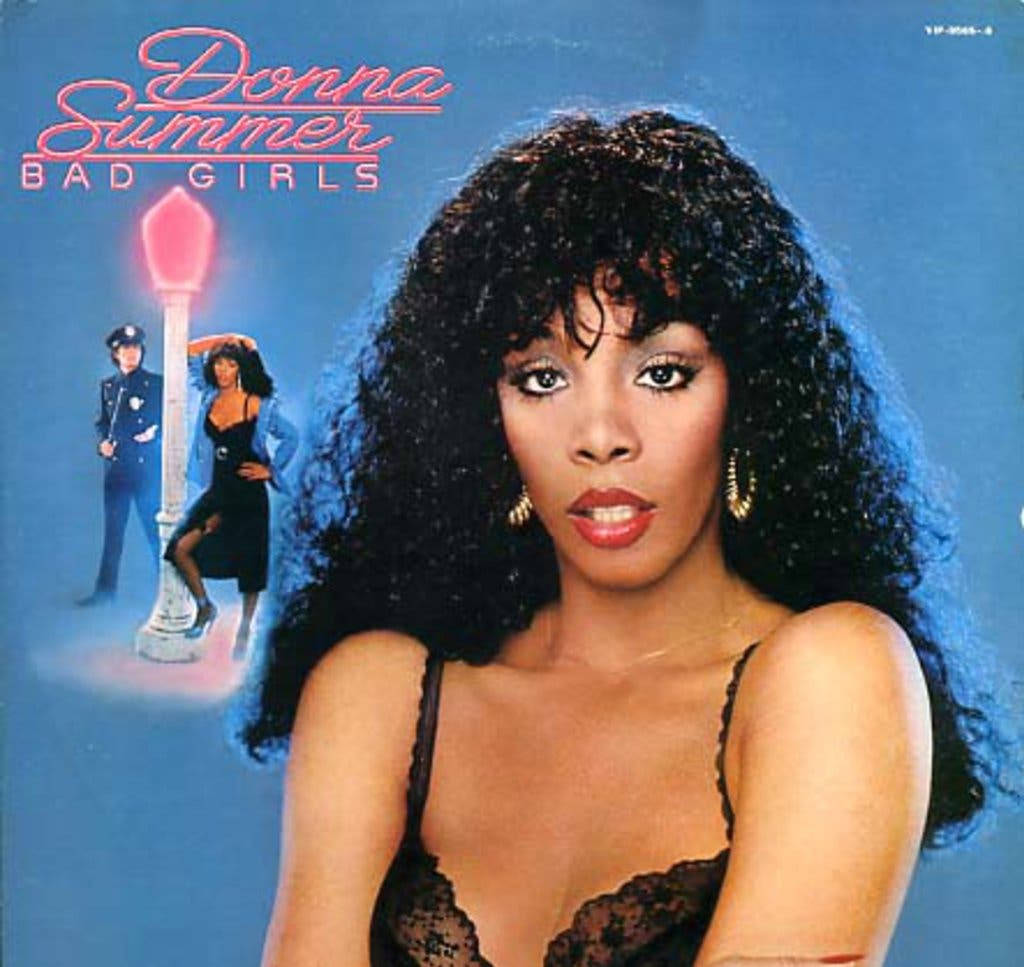 唐娜·蘇默1979年《Bad Girls》專輯封面 壁紙 — Donna Summer 喺藍色背景前強烈凝視，背景有發光嘅粉紅色街燈同一個警察。