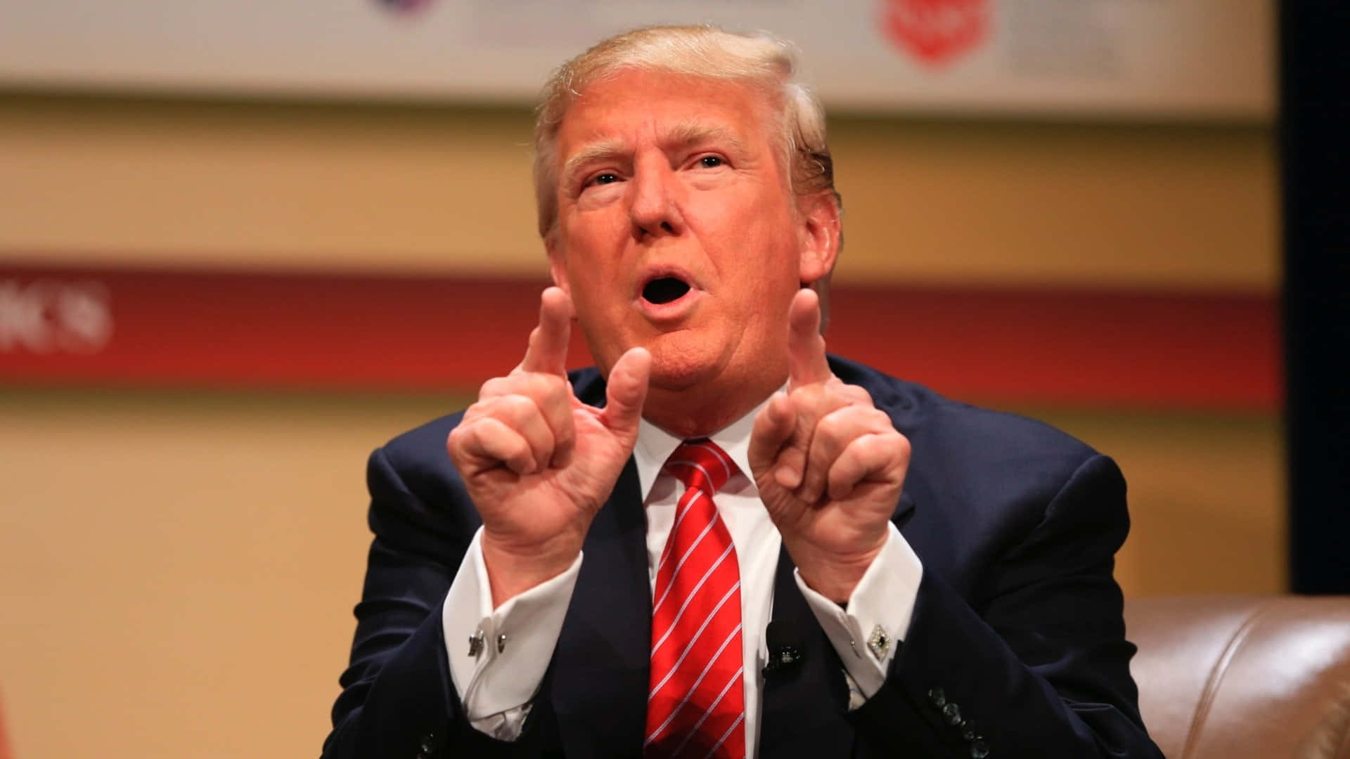 trump 桌布 壁紙 — 唐納德·特朗普在正式場合發言時，強調性地舉起雙食指。