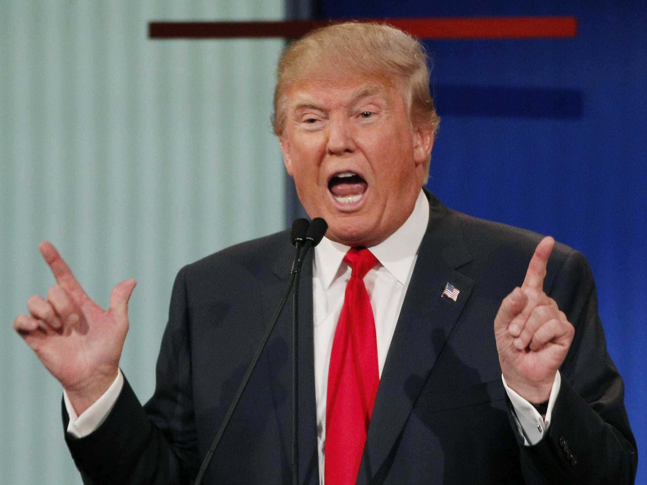 trump 桌布 壁紙 — 唐納德·特朗普身穿深色西裝、繫紅色領帶，在政治活動中對著麥克風說話時，用力地做手勢。