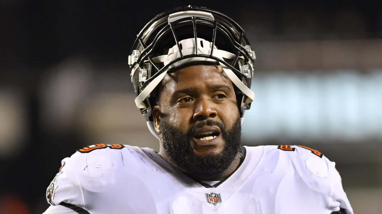 NFL美式足球員身穿白色球衣和頭盔在夜間比賽中。