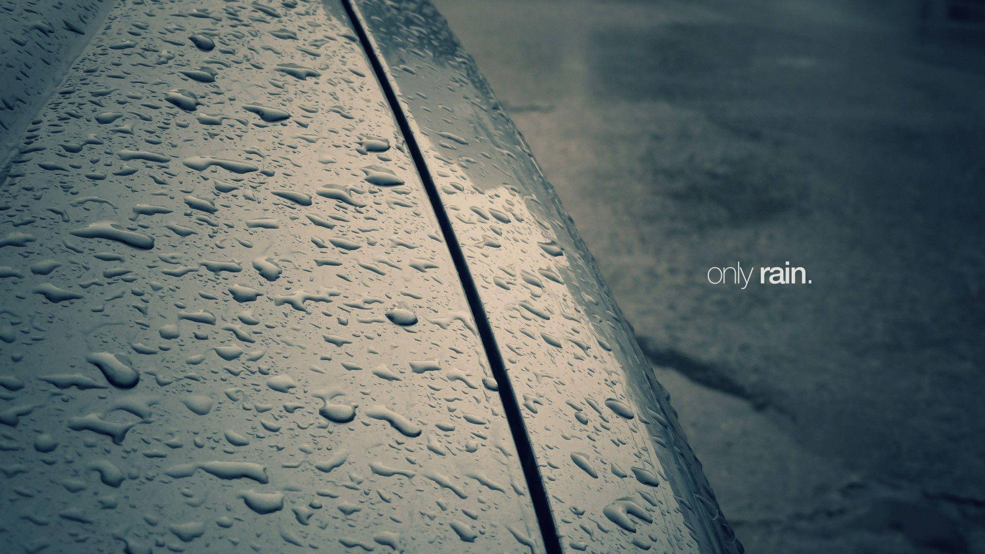 彎曲金屬表面上的雨滴，背景是濕漉漉的路面。