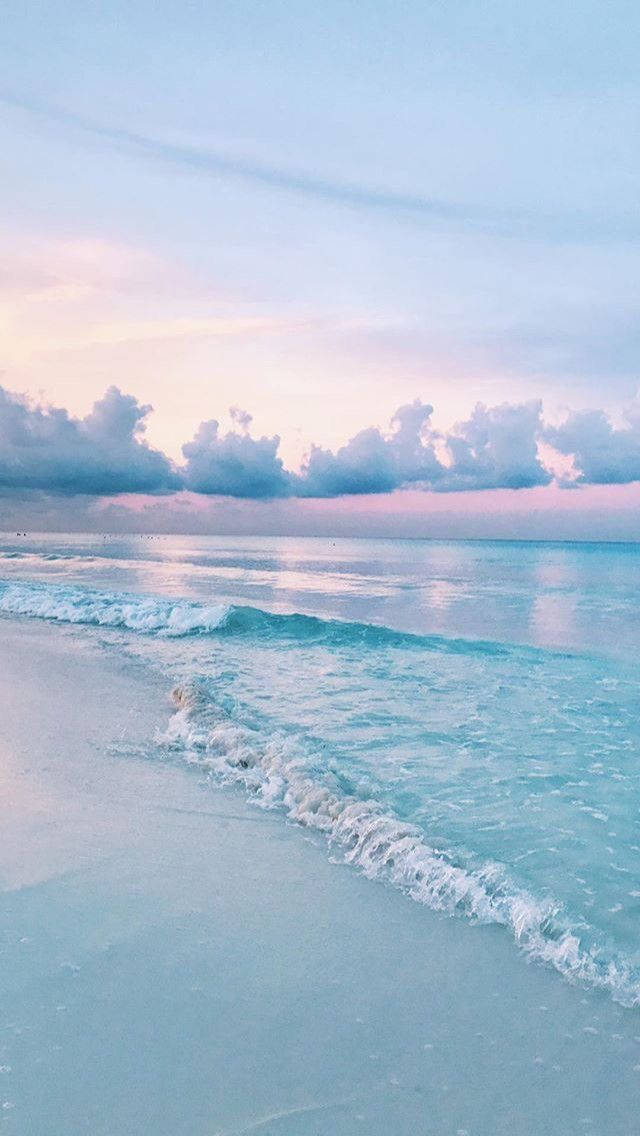 粉彩海灘場景，有柔和波浪同暮色中嘅粉紅藍色天空