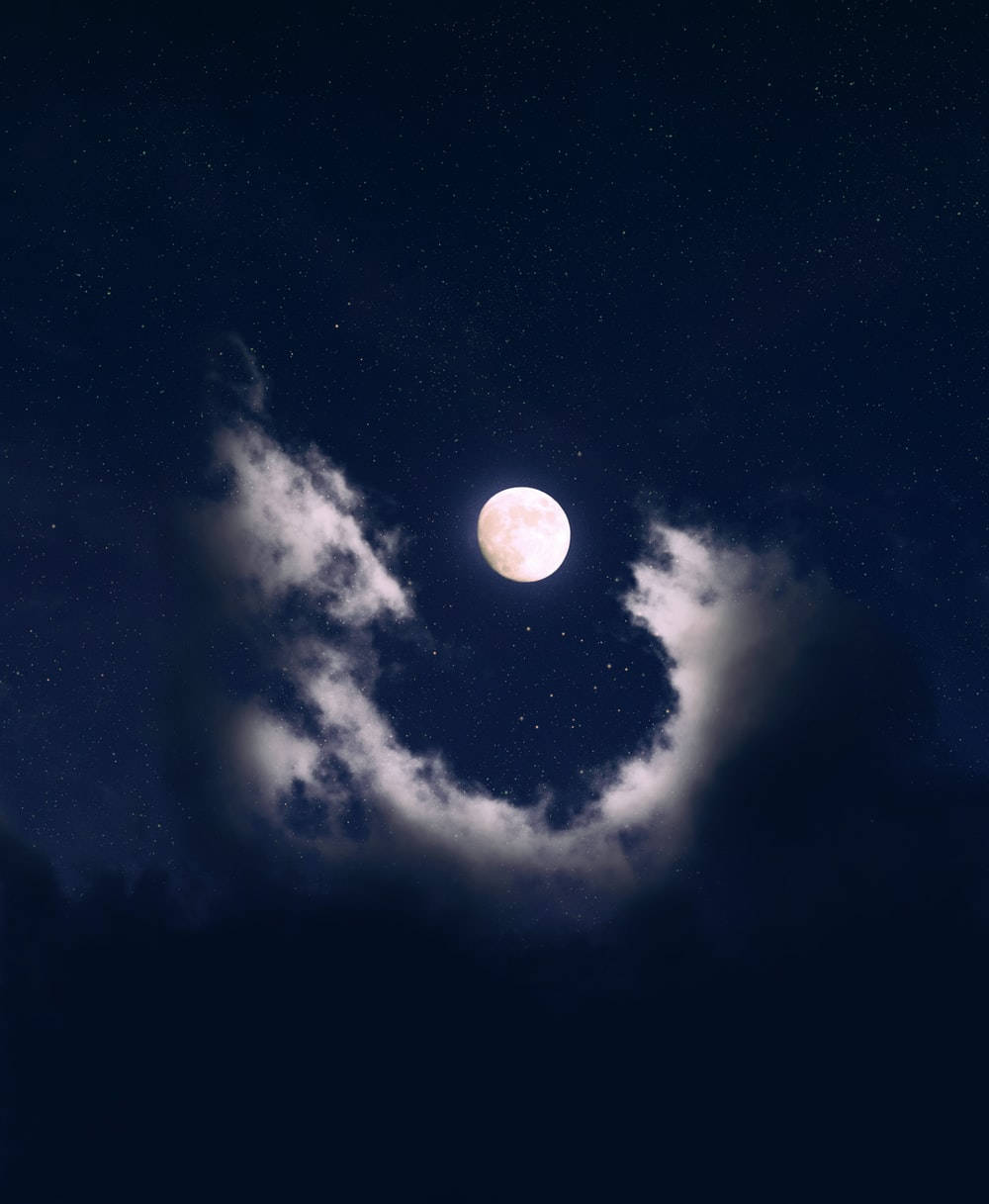 唯美雲朵環繞滿月 壁紙 — 一輪明亮的滿月透過一縷縷薄雲，在繁星點點的午夜天空中閃耀。