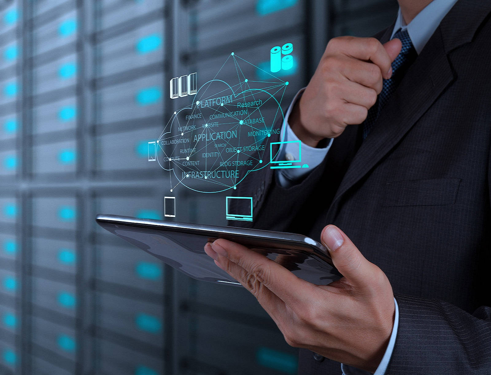 商業科技平台 壁紙 — 一位穿著西裝的商人在伺服器室中，透過平板電腦與發光的全息雲端架構圖進行互動。