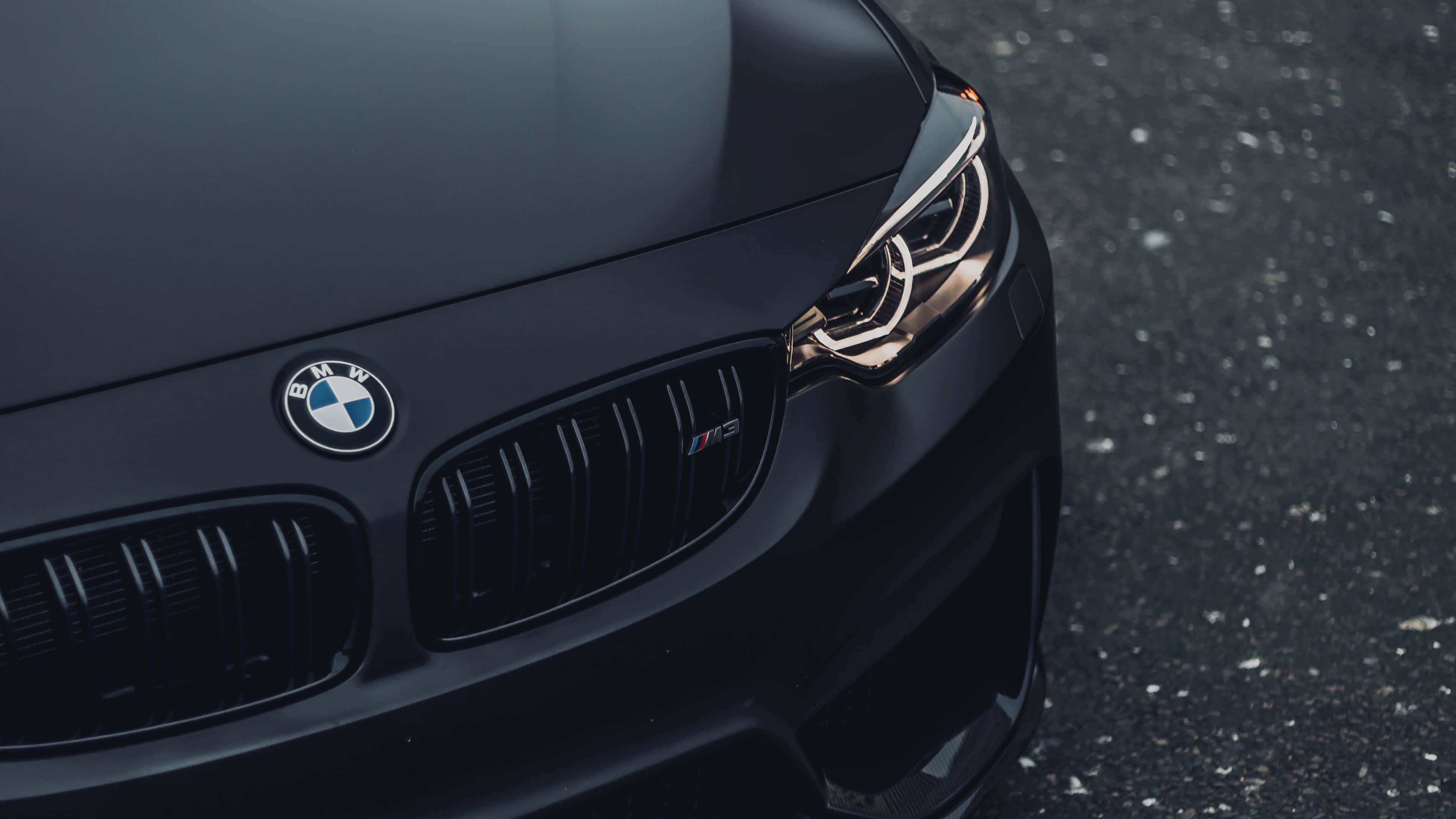 4K BMW 壁紙 桌布 壁紙 — 啞光黑色BMW M3前格柵和發光頭燈在瀝青路面上的特寫。