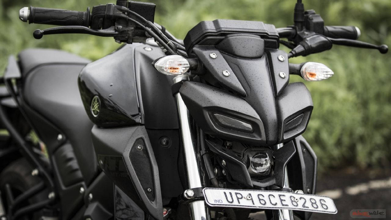 yamaha mt 15 桌布 壁紙 — 啞光黑色Yamaha電單車的特寫，雨滴落在其流線型的前整流罩和把手。