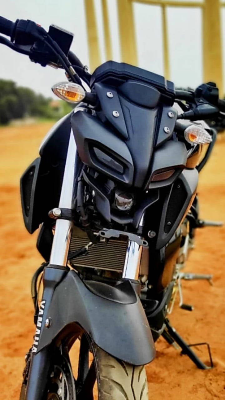 機車 桌布 壁紙 — 啞光黑色Yamaha電單車近距離特寫，停在微紅泥土上，背景有模糊的黃色結構。