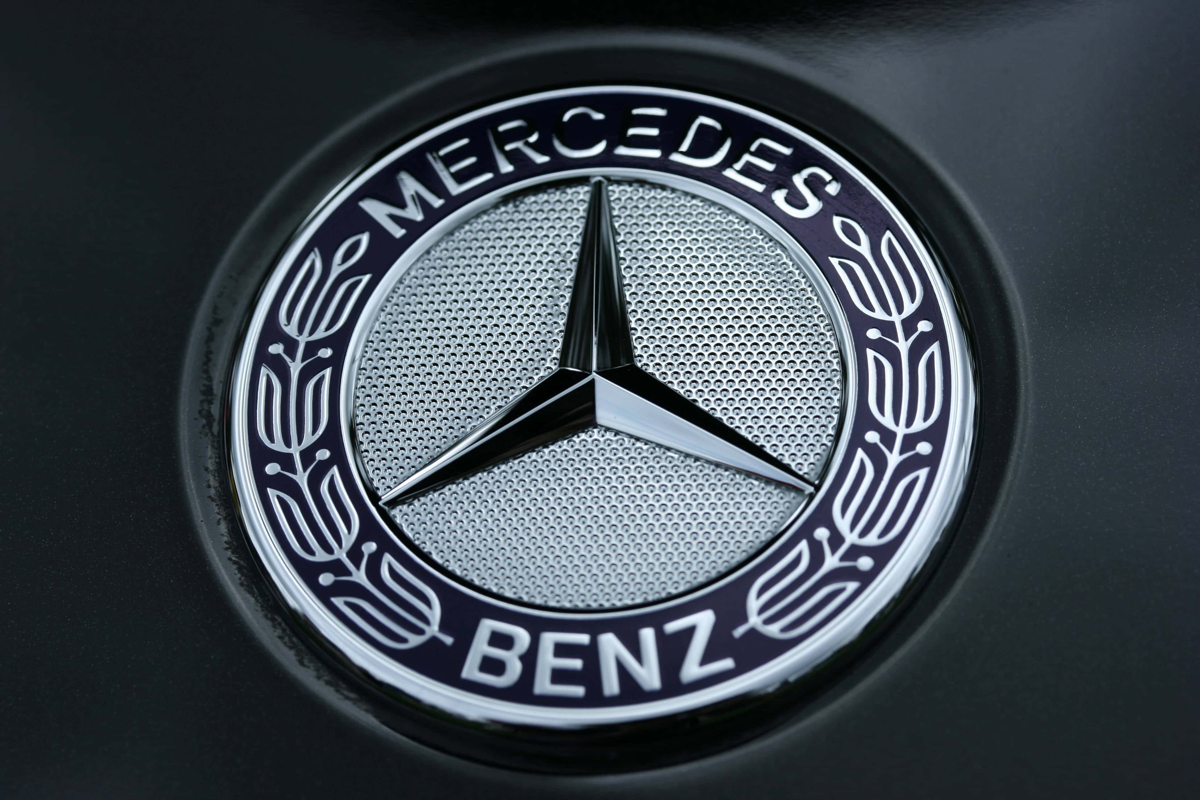 Car Logo 桌布 壁紙 — 啞光黑色汽車引擎蓋上閃閃發光的平治標誌特寫，細節精緻。