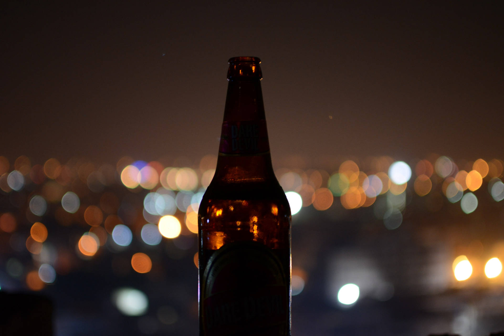啤酒瓶剪影，背景是模糊的城市夜燈。
