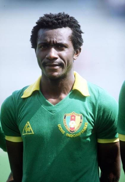 身穿綠色和黃色Lions Indomptables球衣的黑人足球員對著鏡頭微笑。