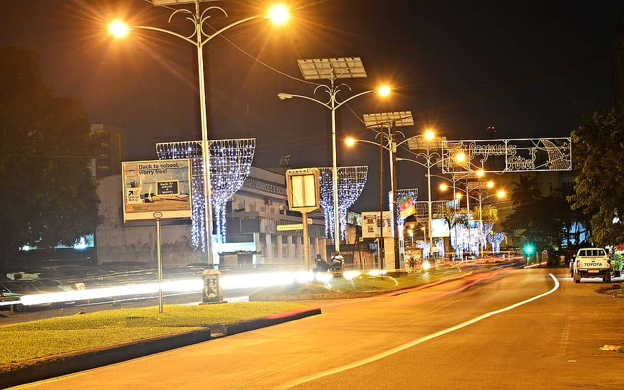 夜晚的城市街道，閃爍的路燈和節日裝飾，模糊的車燈光線劃過道路。