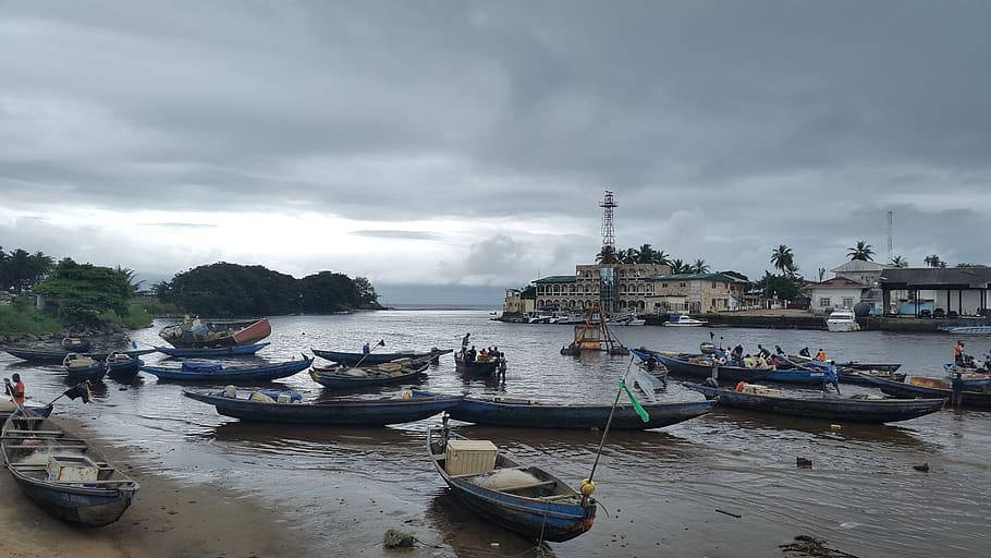 多雲天空下，海濱建築附近泥濘岸邊的漁船