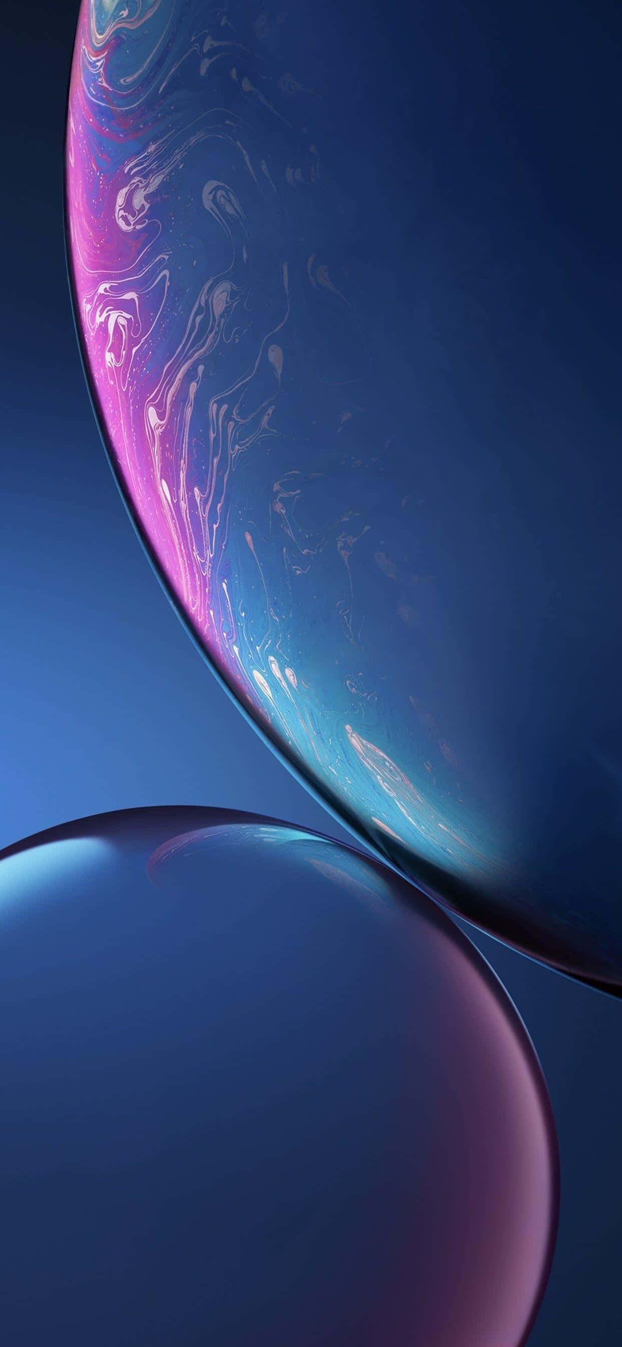 善用每一刻，體驗 Apple iPhone XS Max 壁紙 — 兩個帶有旋轉粉紅色和藍色液體圖案的光澤球體漂浮在深藍色漸變背景上。