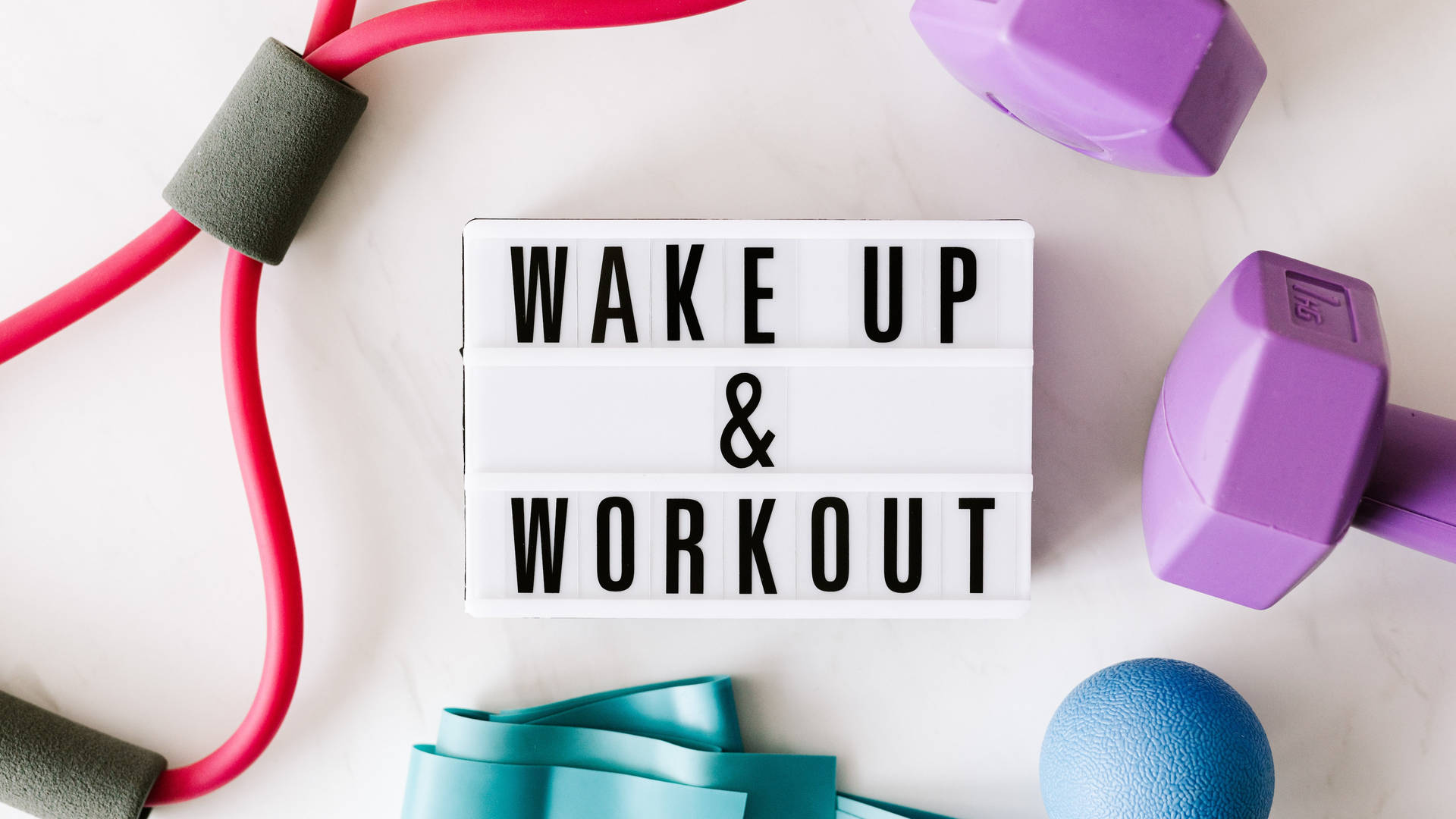 健身器材圍繞著一個寫著 wake up and workout 的標誌排列。