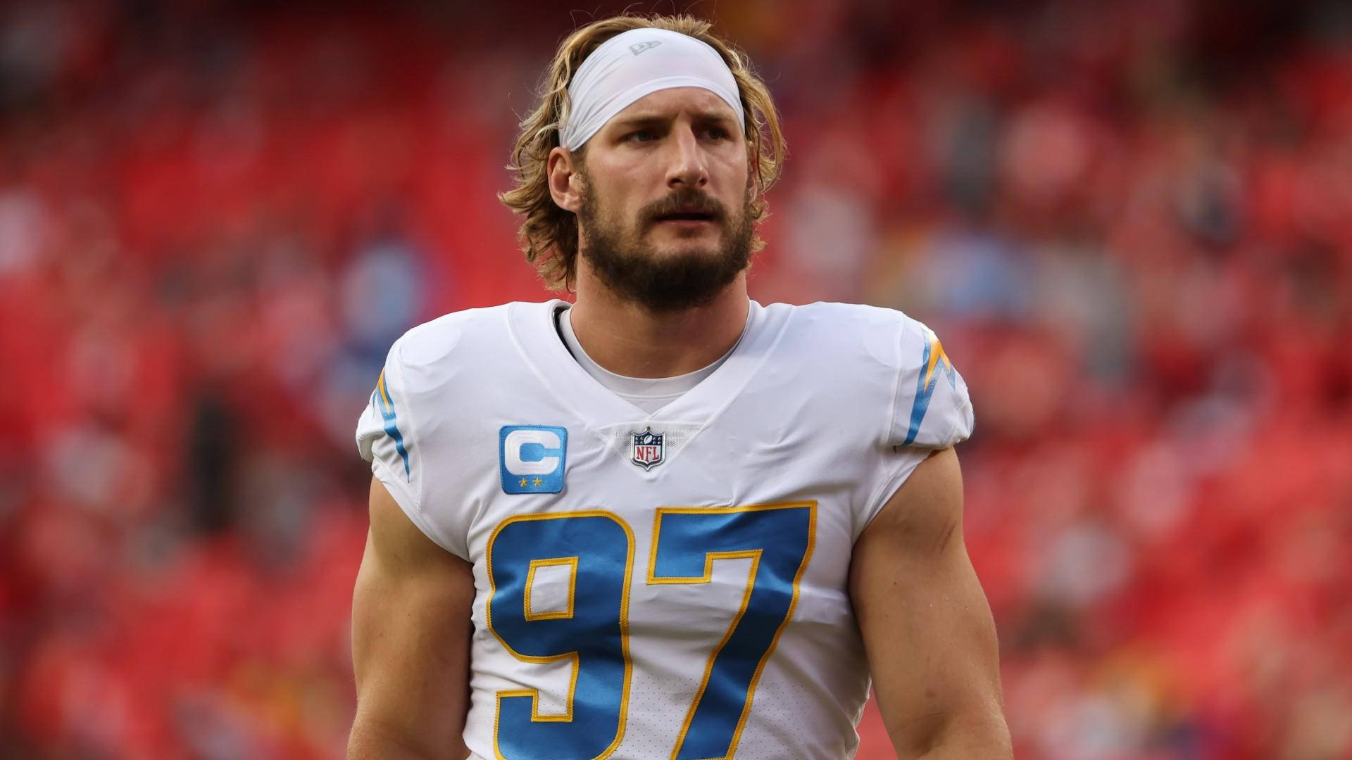 NFL球員身穿白色球衣號碼97，帶有藍色和金色點綴，站在足球場上。