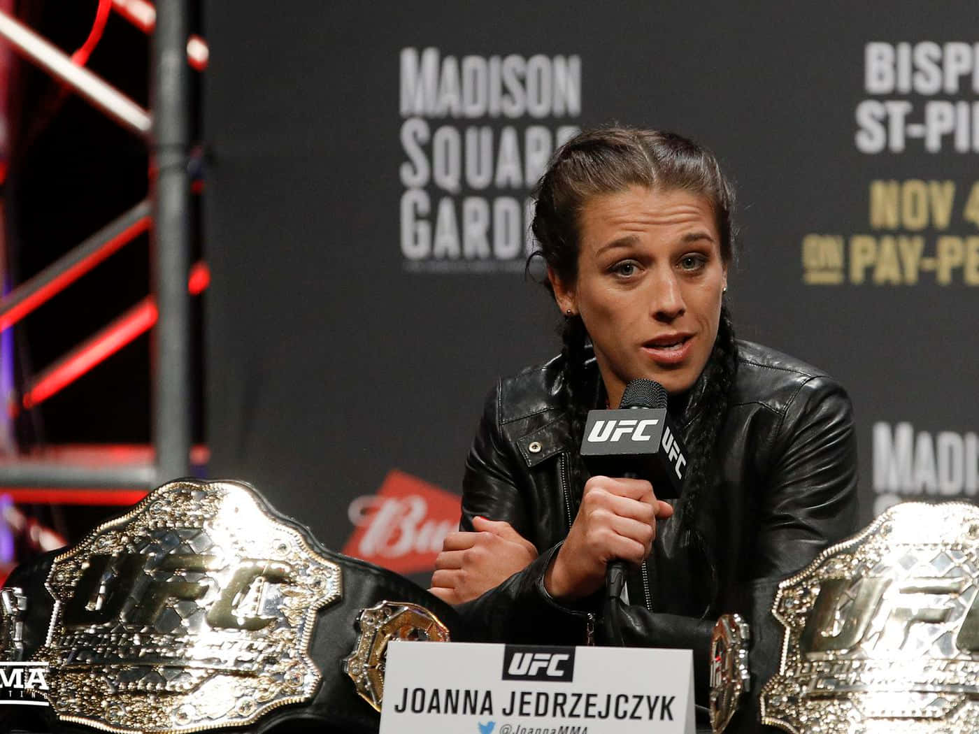 UFC拳手Joanna Jedrzejczyk在新聞發布會上發言，身旁有冠軍腰帶。