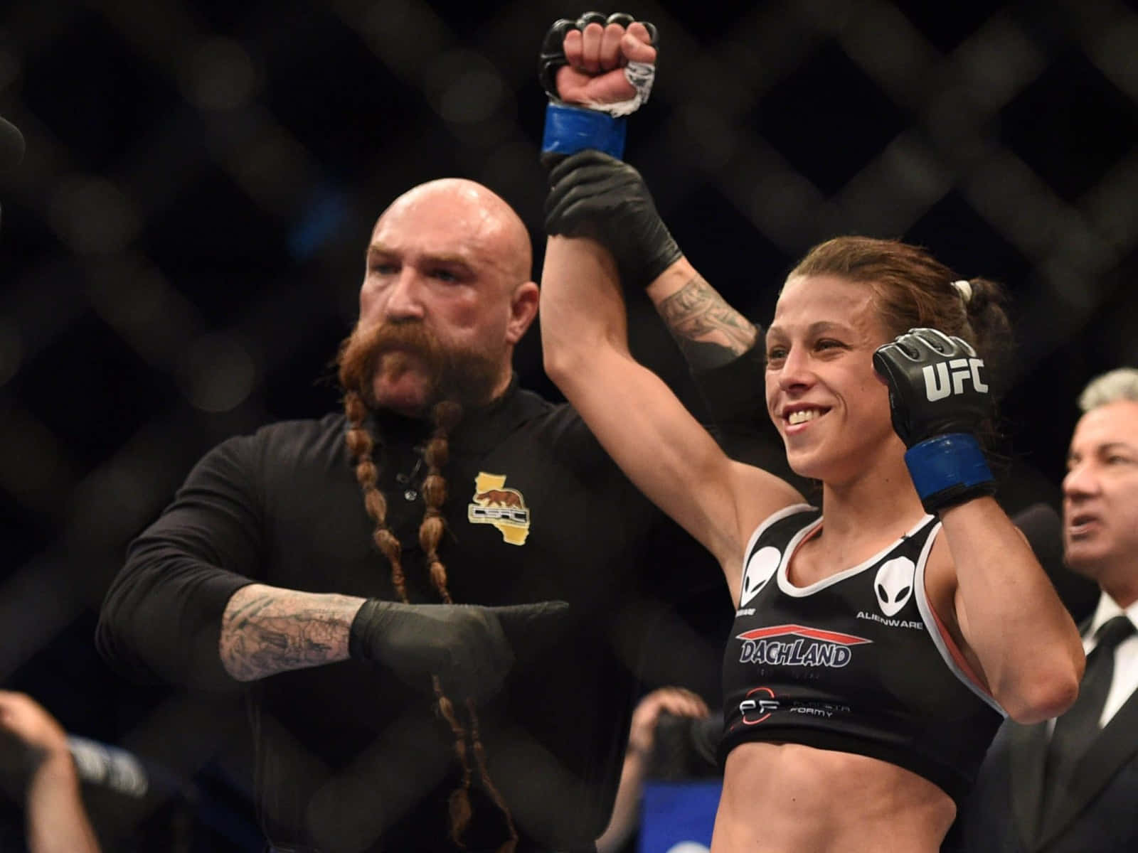 女性MMA拳手高舉拳頭慶祝勝利，裁判舉起她的手。