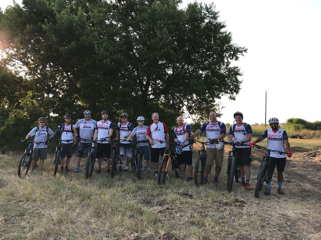一群山地車手在日落時於樹下與單車合照。