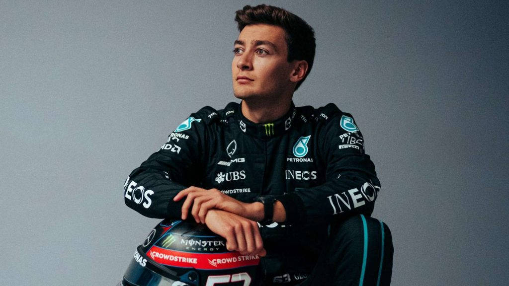 F1車手穿著賽車服在攝影棚內將手放在頭盔上