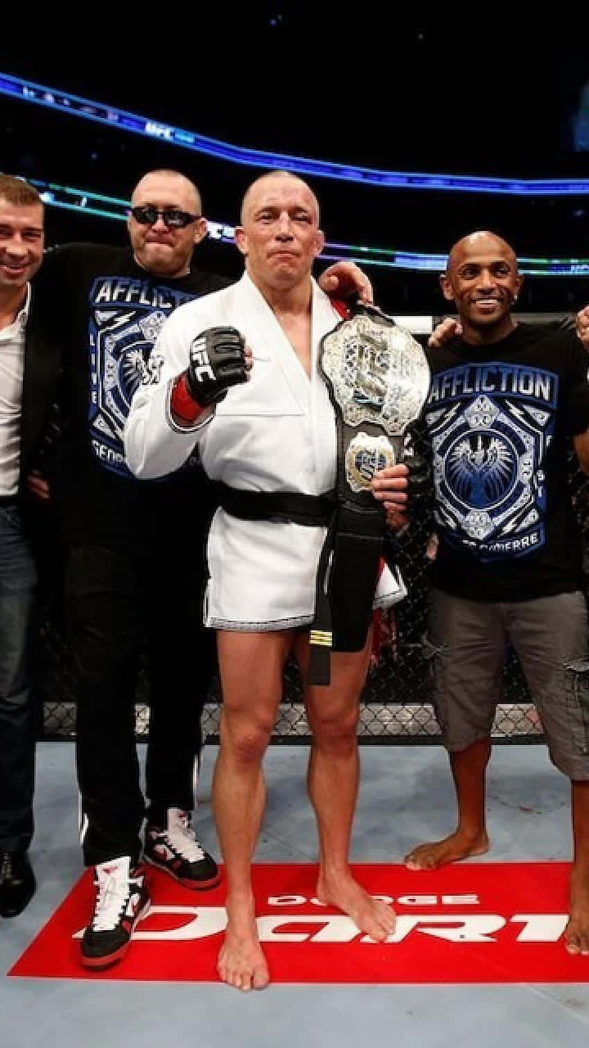 MMA選手在八角籠中與隊友高舉冠軍腰帶