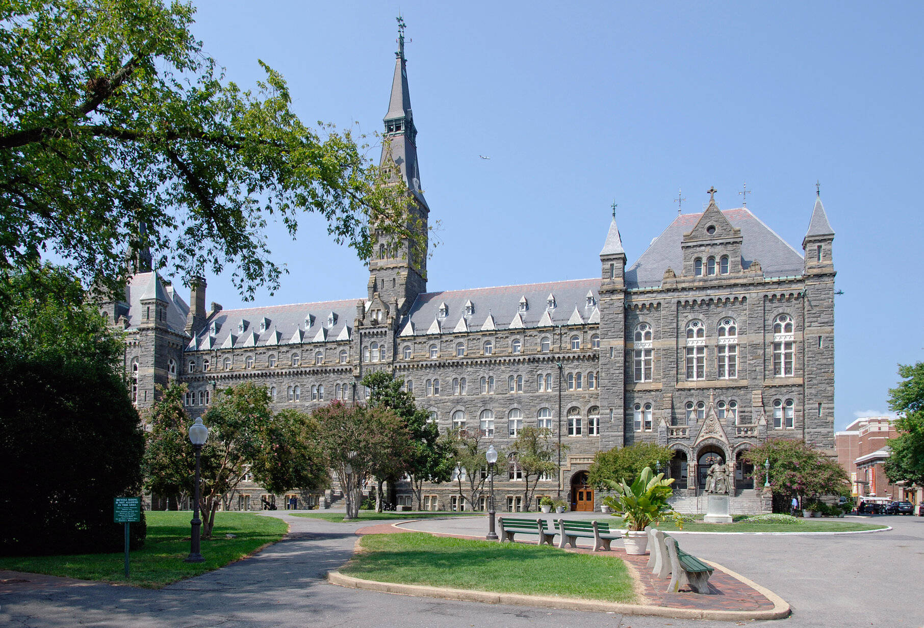 歷史悠久的石造大學建築，帶有尖塔和綠色草坪，在藍天下