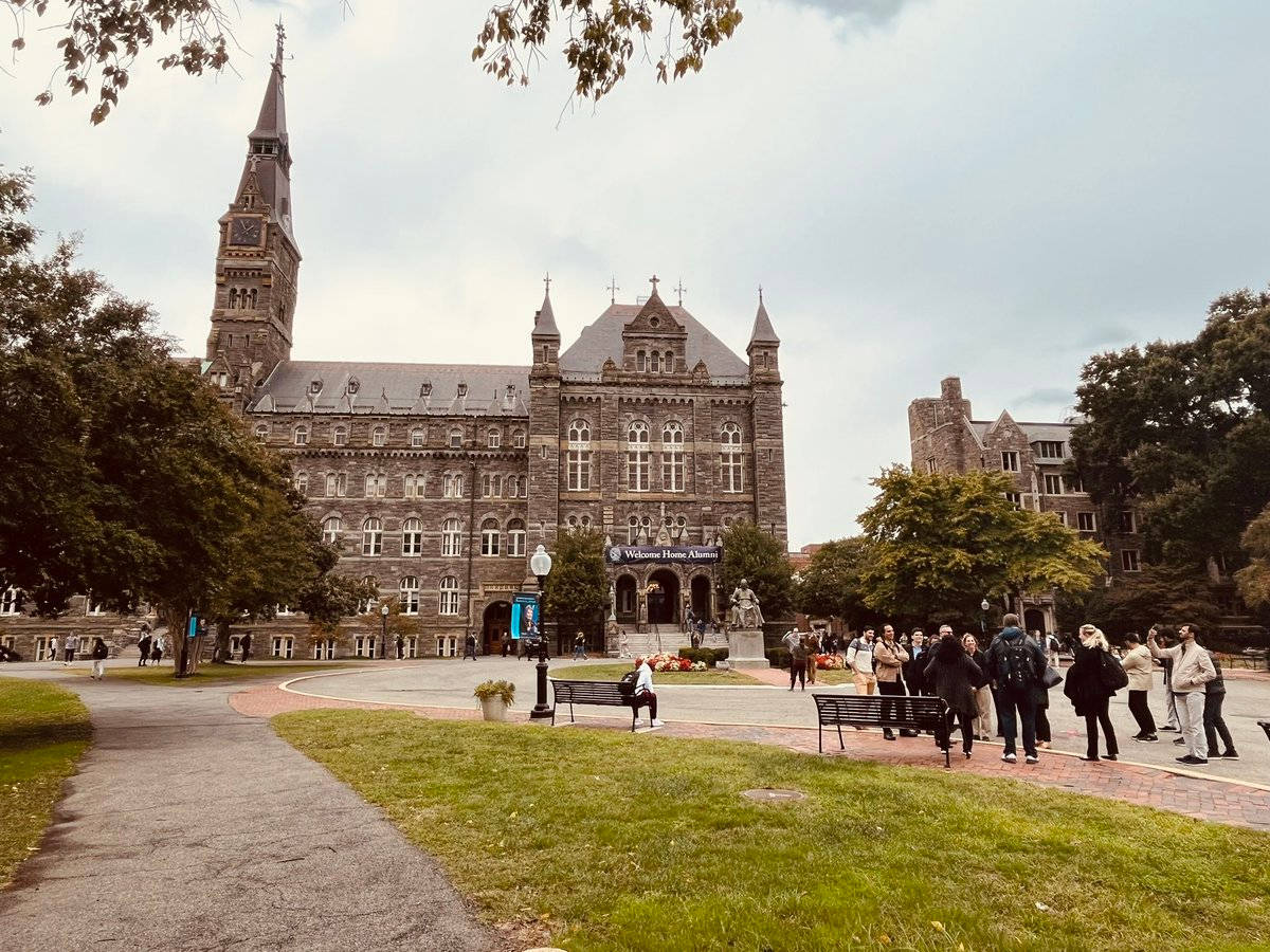 學生們走近一座帶有鐘樓的歷史石造大學建築。