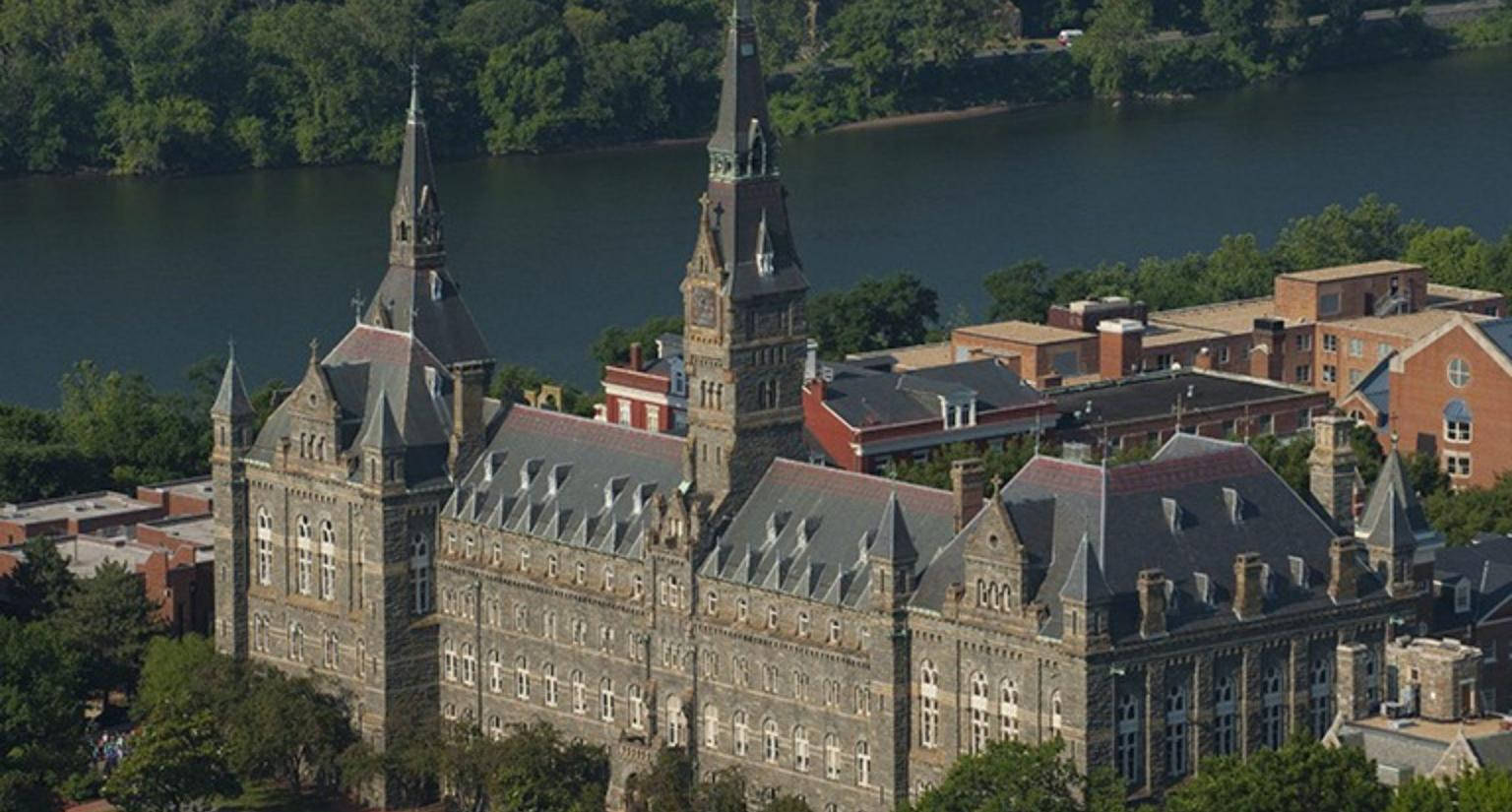 宏偉的石造大學建築，帶有尖塔，俯瞰河流和綠樹。