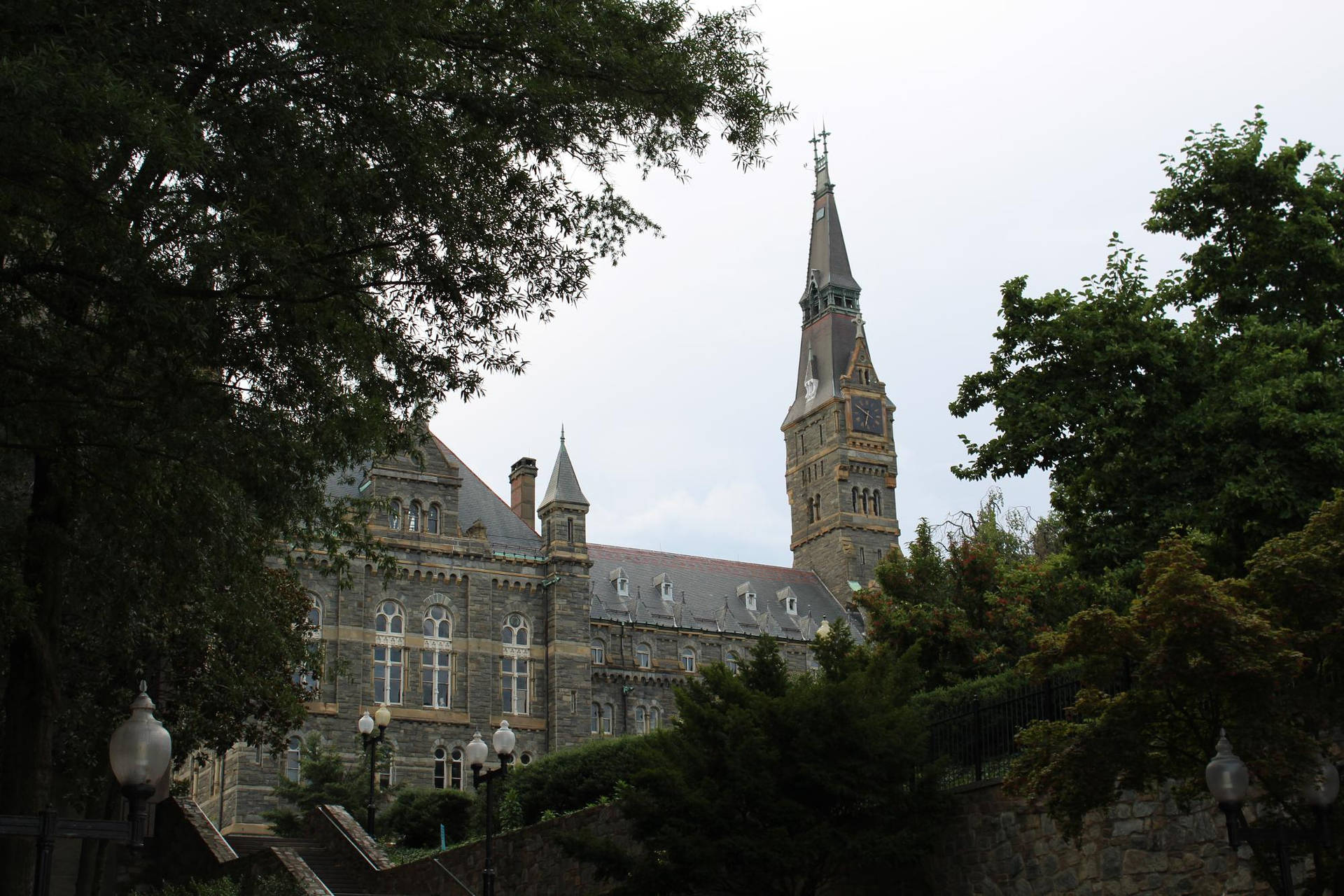 歷史悠久的石造大學建築，鐘樓在陰天被樹木環繞。