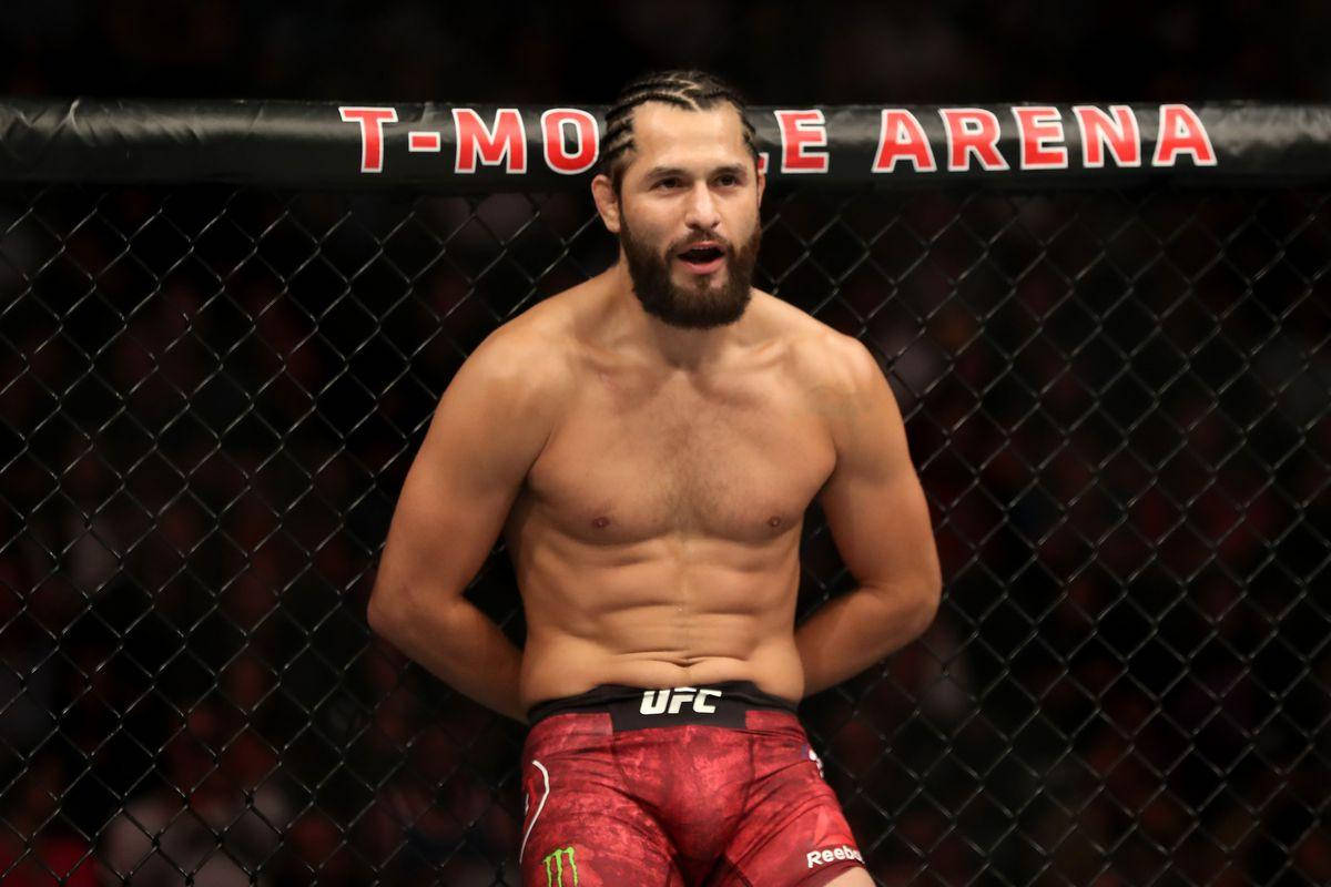 一位赤裸上身的MMA戰士穿著紅色短褲，站在T-Mobile Arena的格鬥籠內。