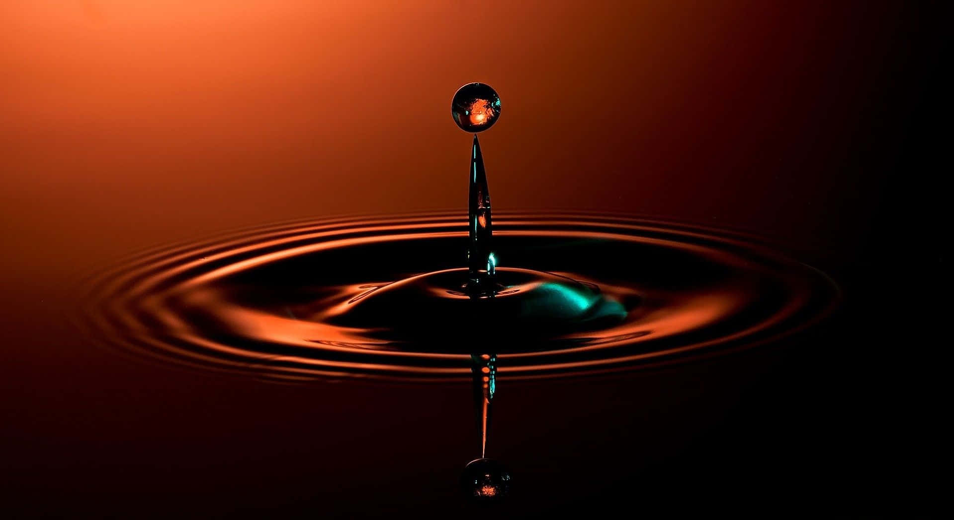 3d Water 桌布 壁紙 — 單一水滴懸浮在深色表面上，在溫暖的橙色燈光下形成完美的同心漣漪。