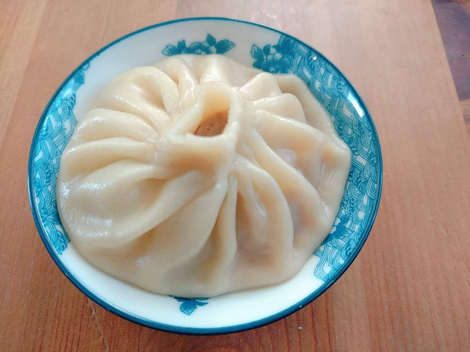 藍色花卉碗中的蒸餃，木桌