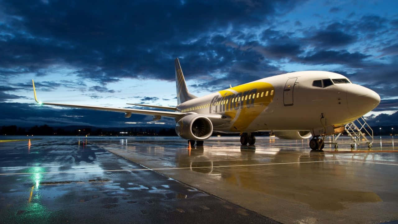 單獨飛機飛越廣闊雲層 壁紙 — 一架瑞安航空飛機停在濕滑的停機坪上，天空呈現戲劇性的暮色，雲朵倒映在被雨水浸濕的地面。