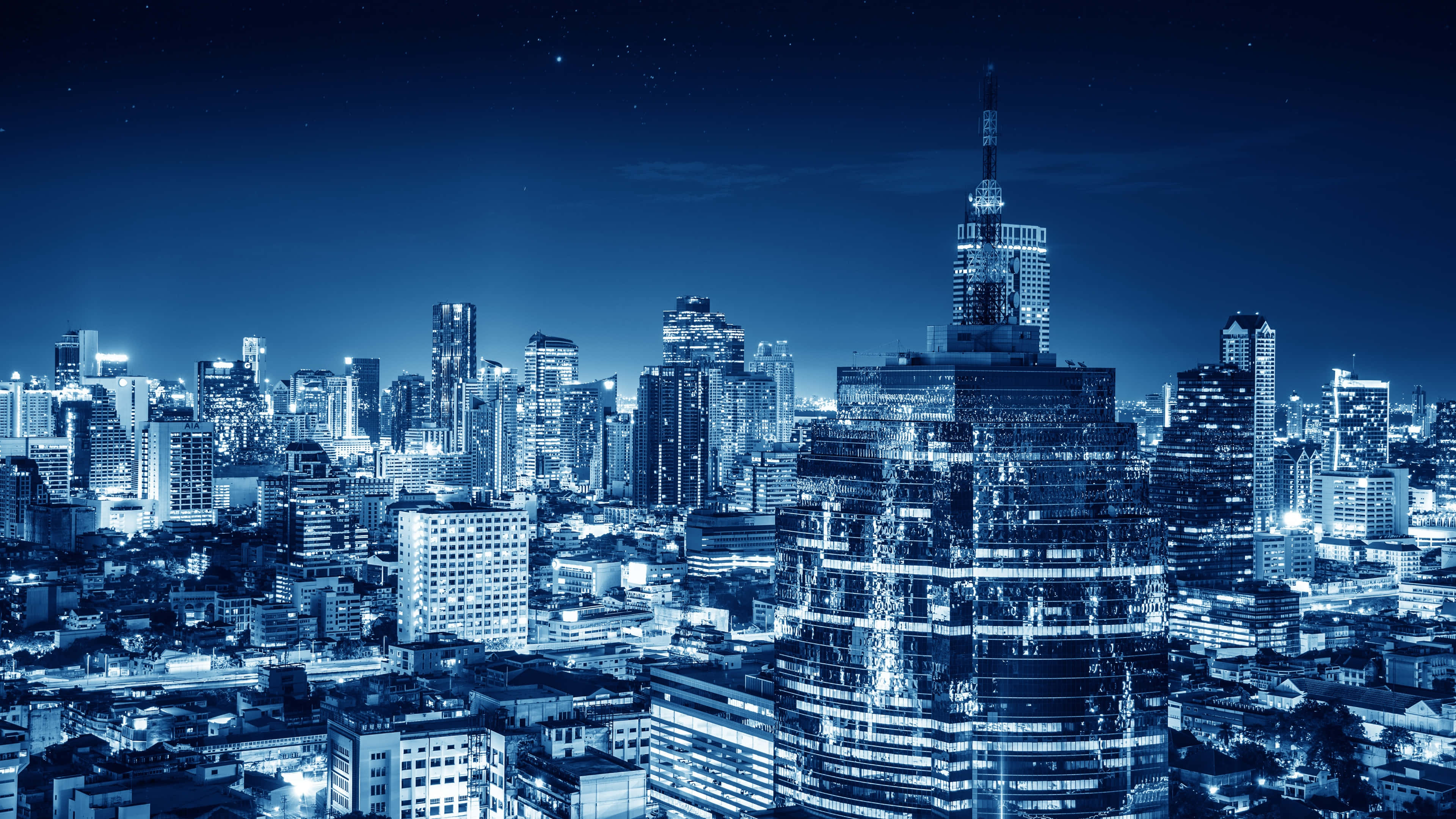 單色城市夜景 壁紙 — 廣闊的城市天際線夜景，沐浴在清涼的藍色調中，無數窗戶在星空下閃爍。