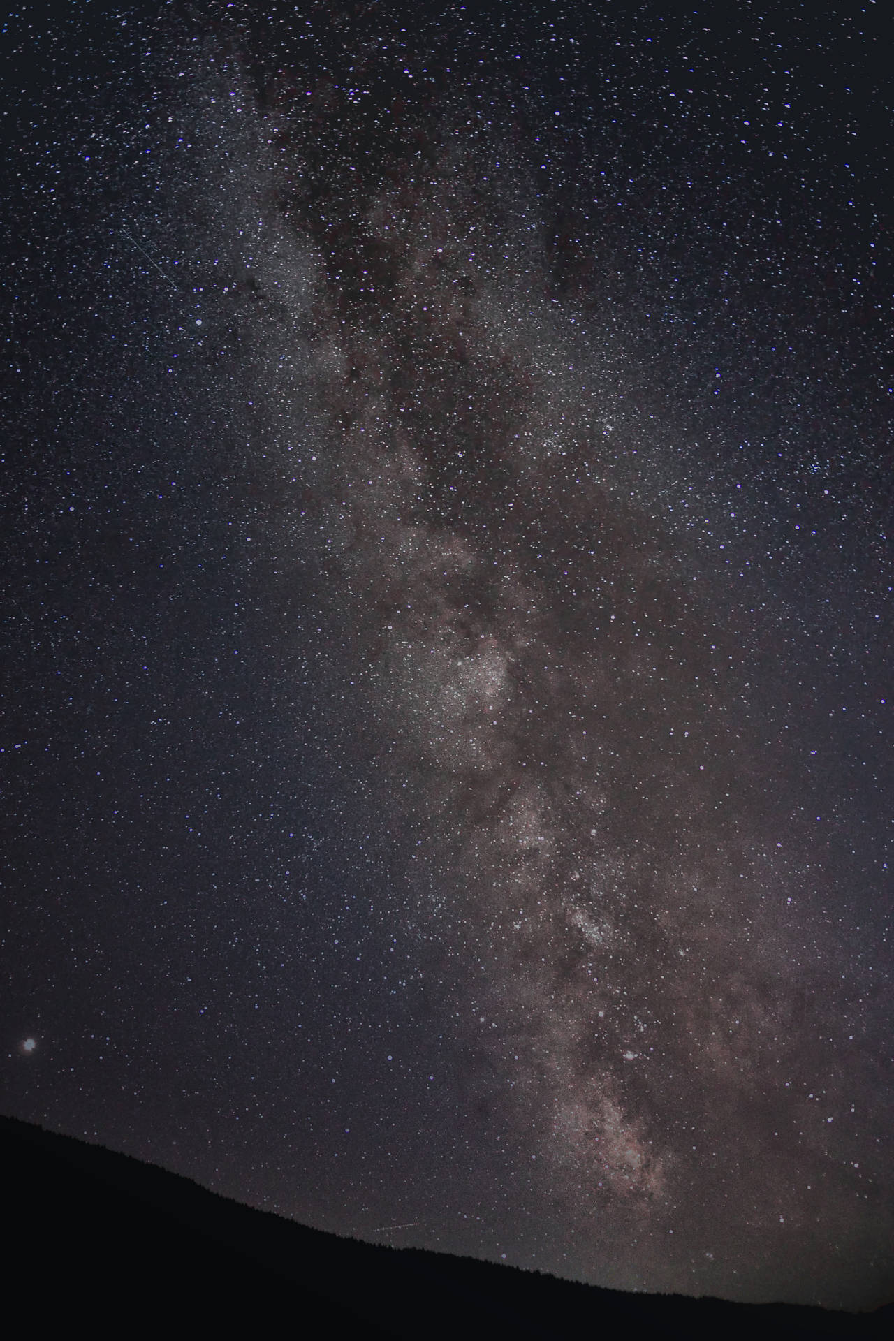 夜晚，銀河系在山脈上方發光。