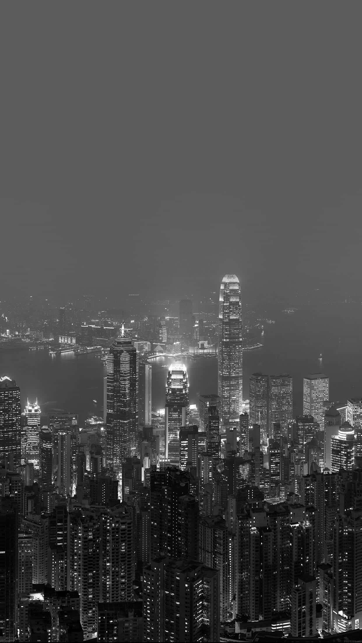 暗夜城市 桌布 壁紙 — 單色夜間城市景觀，高聳的摩天大樓在朦朧的天空中閃爍著燈光。